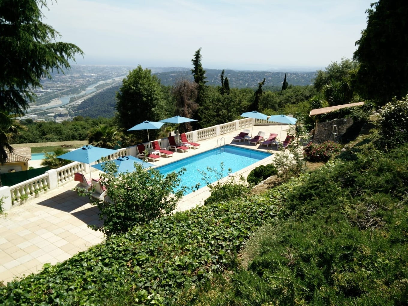Terrasse de piscine avec parasols et vue sur la vallée.