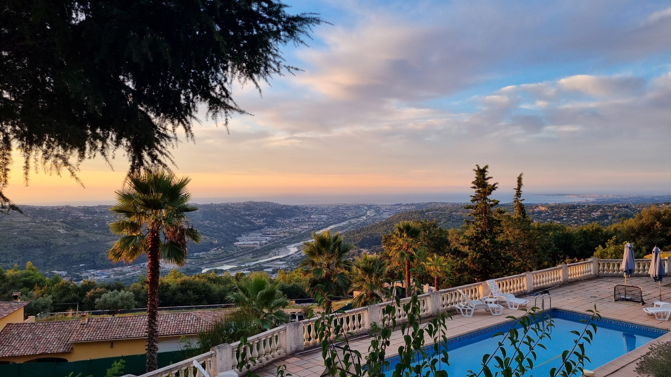 Vue sur la piscine et la vallée jusqu’à la côte méditerranéenne au soleil couchant.