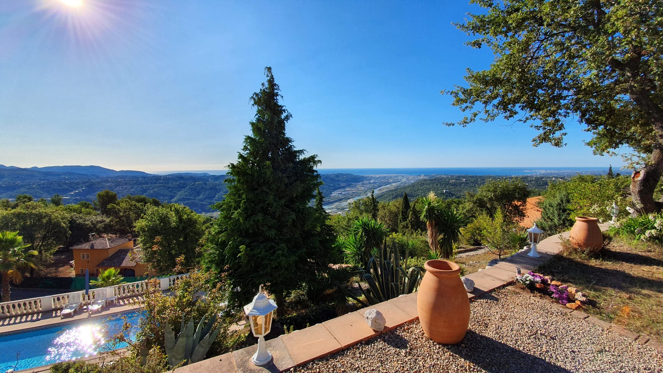 Vue depuis la terrasse sur la piscine, le jardin et la côte.